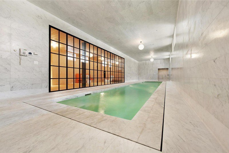 Inomhus-pool-marmorplattor-dränering-glas-dörrar-moderna