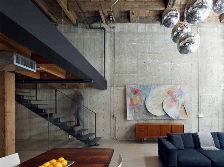 industriell design vardagsrum betong trä loft karaktär ljuskrona metall svarta rör