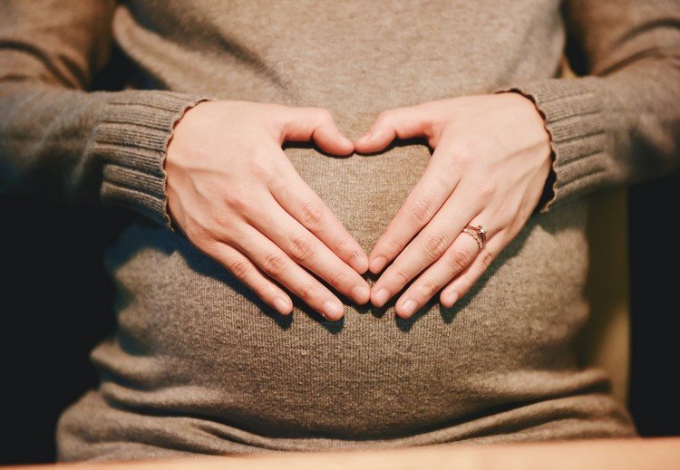 Gravid kvinna i vintern händer på baby bump