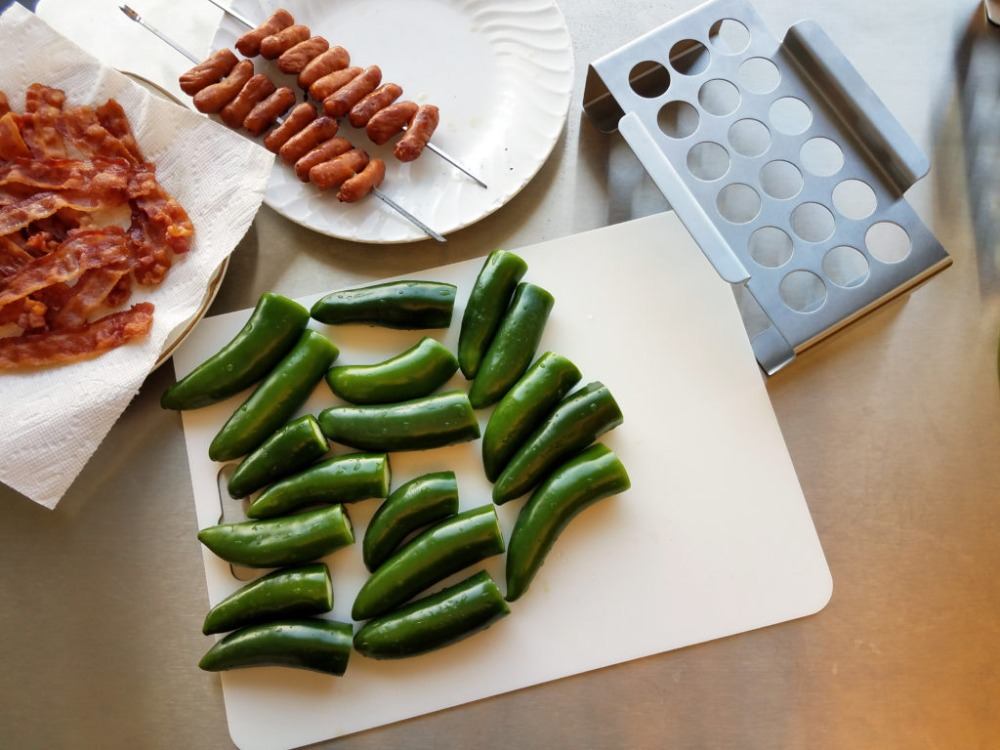 stekta baconskivor och korv i kombination med grön chilipeppar på köksbrädan