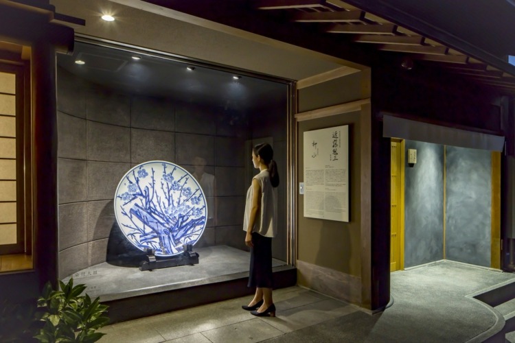 Museumsbesöksutställning traditionell japansk keramikplatta aprikosträd