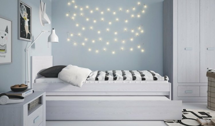 vita möbler och älvlampor som dekoration på en ljusblå vägg