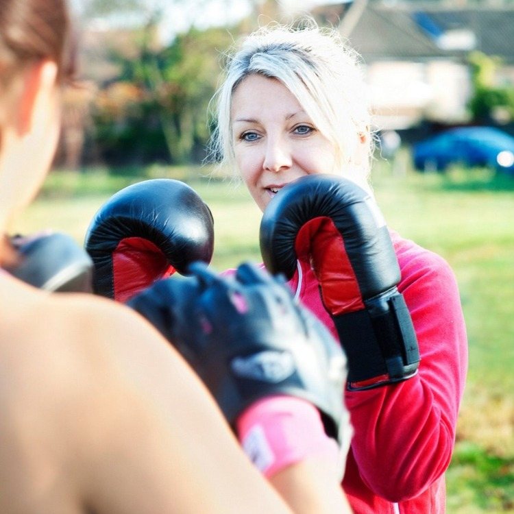 motiverad kvinna som bränner kalorier medan hon tränar för kickboxning eller boxning