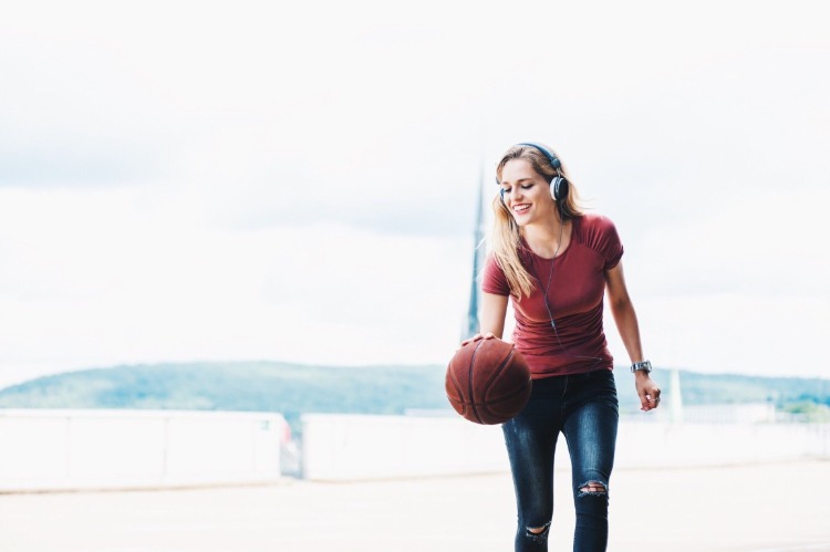 leende ung kvinna med hörlurar och basket som en sport för att gå ner i vikt