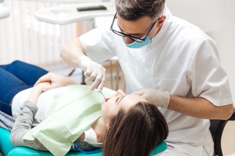 Professionell tandläkare behandlar kvinnlig patient med medicinska instrument