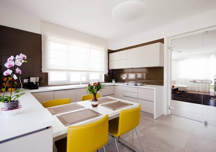 paninsula förlängning som matbord med gula stolar i ett stort kök med glasdörr