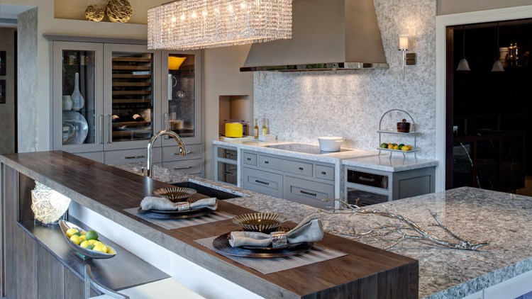 Köksö med träbänk i modern lantlig stil, grå köksskåp och bänkskiva i granit tillsammans med trästrum