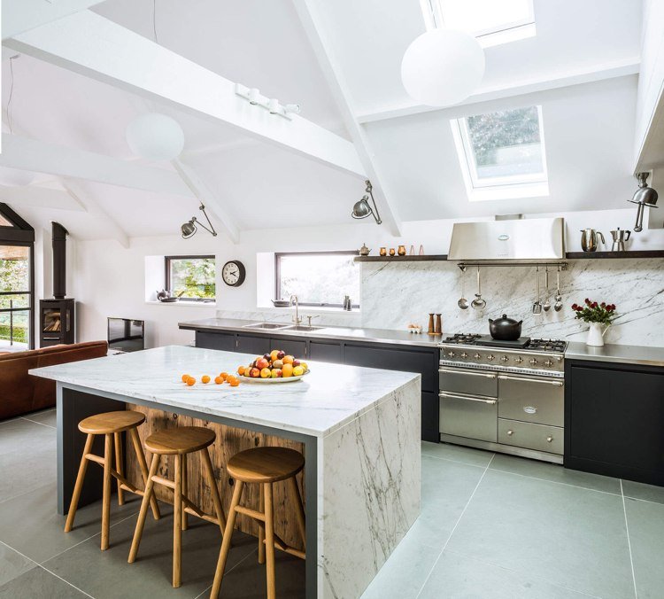 Modernt kök under snett tak med köksö med liten bänk utan vitvaror av trä och marmor