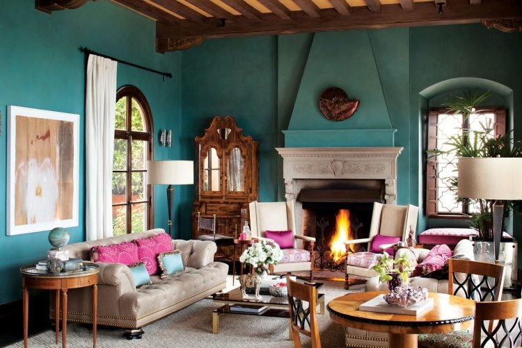 kudde-turkos-vardagsrum-öppen spis-antika stoppade möbler-rosa-ljusgrå-väggfärg-träbjälkar