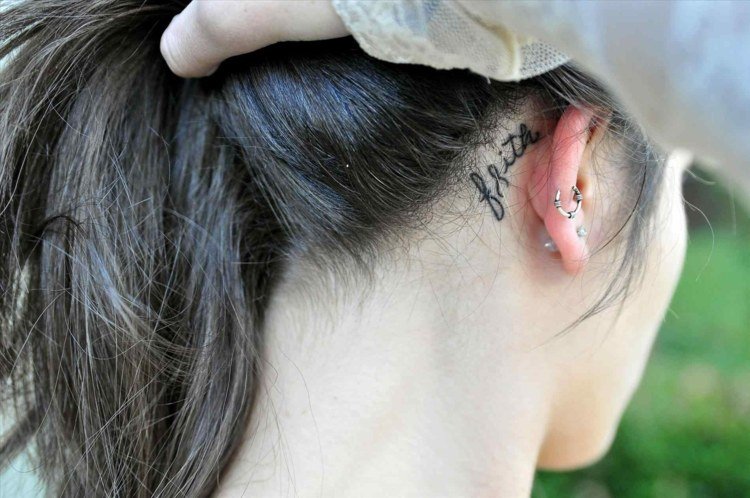 små tatueringsmotiv för kvinnor bakom örat som skriver svart