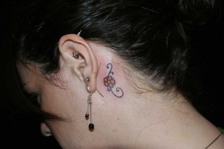 små tatueringsmotiv blommor filigran färgstarka bakom örat