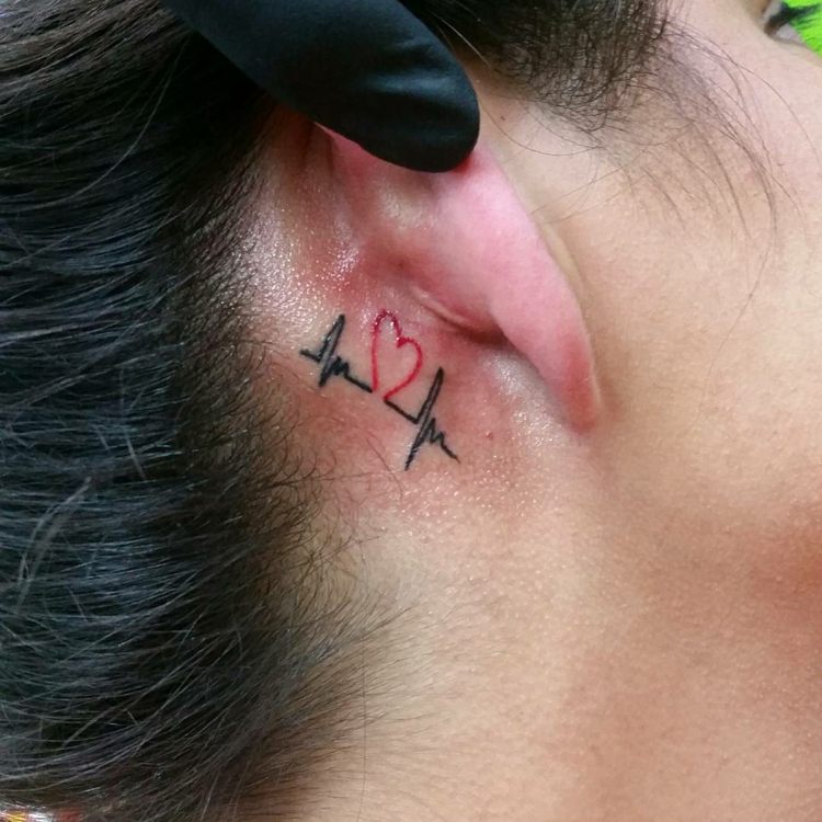 små tatueringsmotiv hjärta hjärtslag kvinna svart röd bakom örat