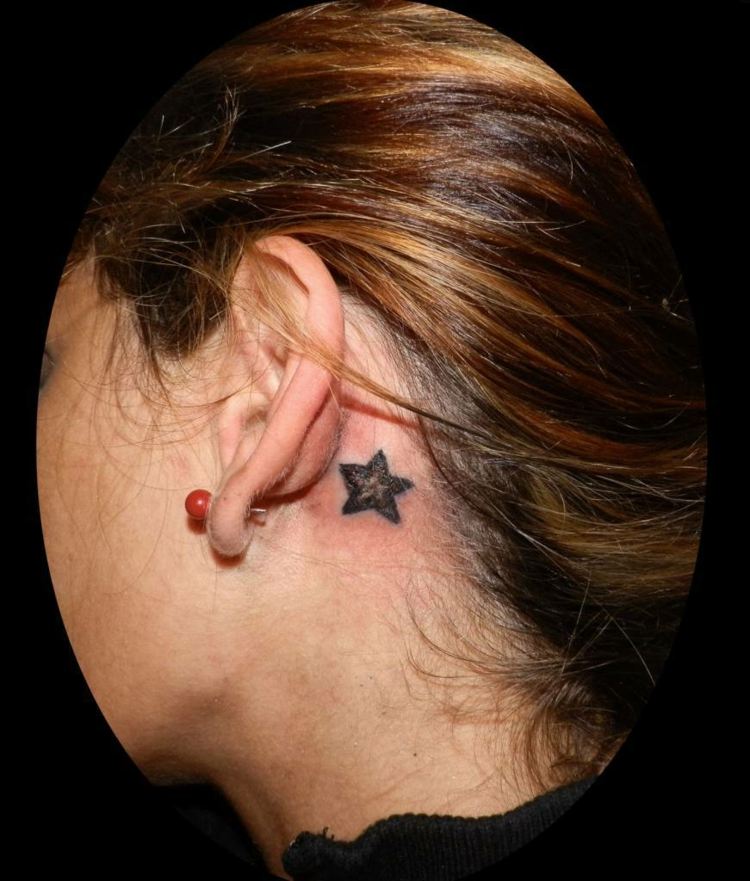 kvinna små tatuering motiv stjärna bakom örat