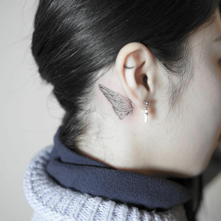 små tatueringsmotiv vingar bakom örat diskret kvinna