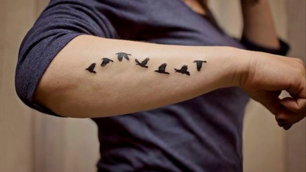 flygande fåglar avbildade som små tatueringar män för ett subtilt utseende