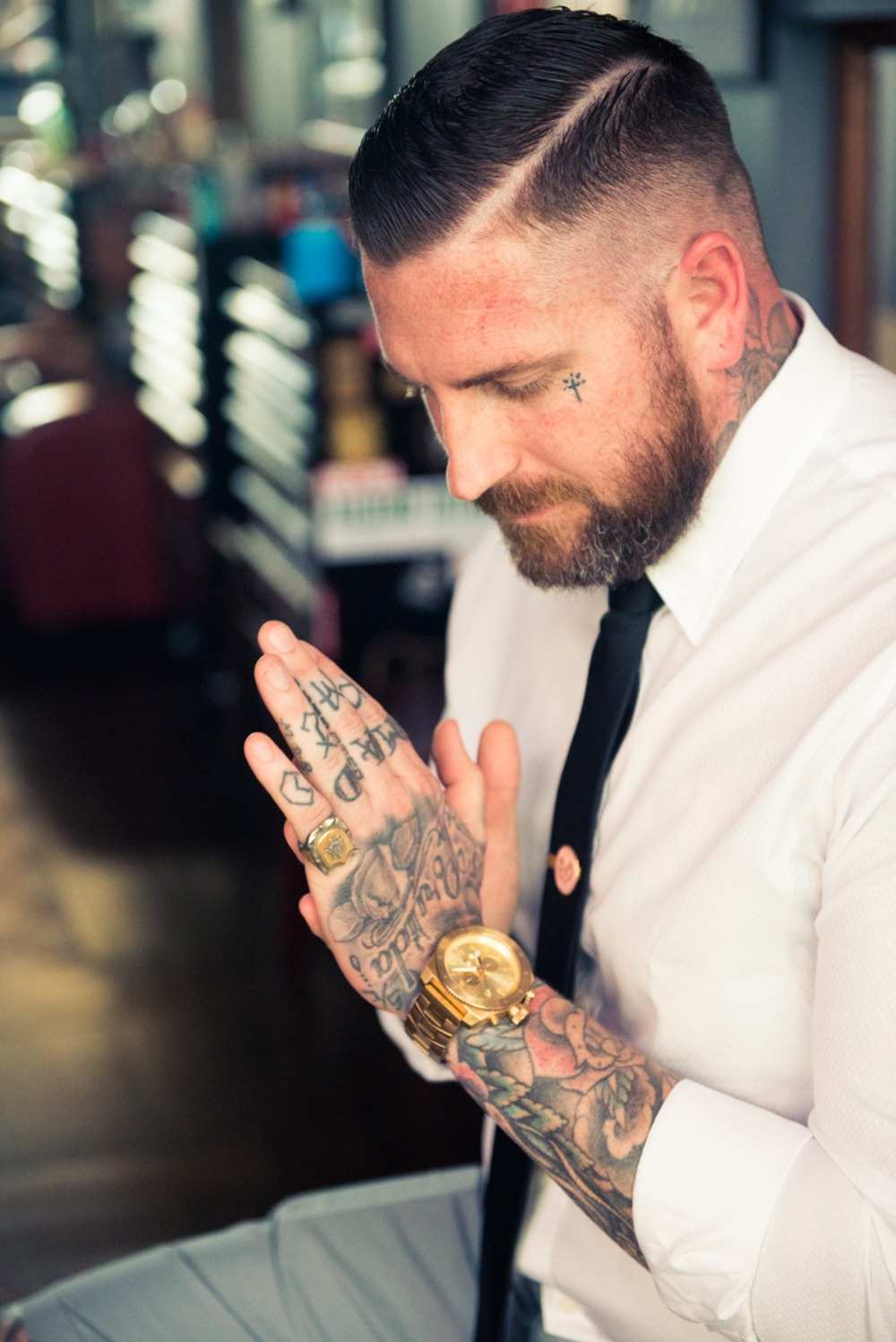 tatuering liten man i ansiktet kors tatuering och ärm tatueringar på fingrarna