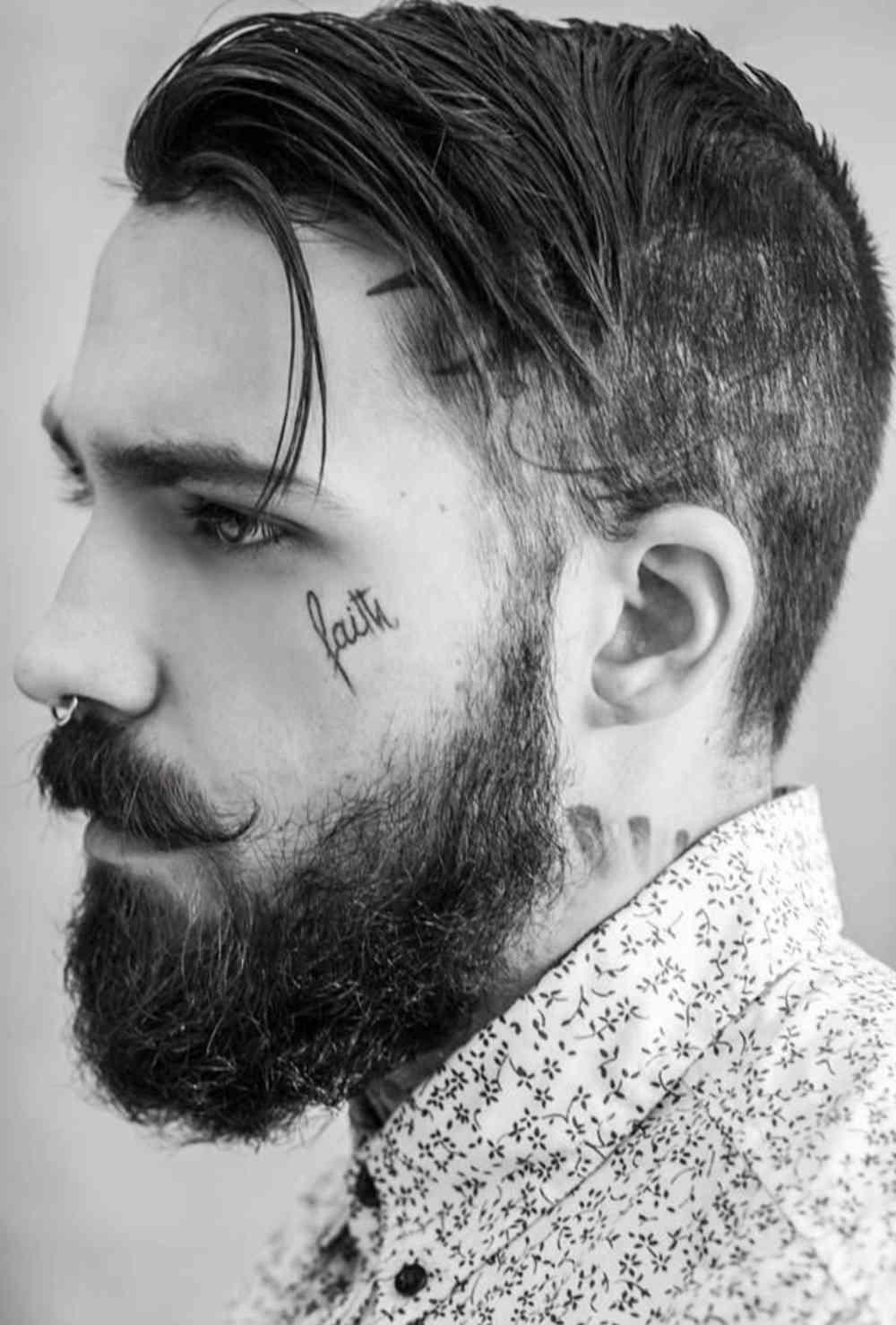 Tatuering i ansiktet från små bokstäver av en man med skägg