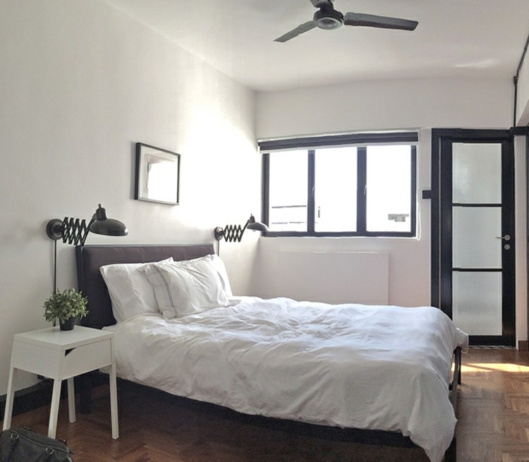 liten lägenhet-inredning-sovrum-svart-stoppad säng-sängbord-vit-parkettgolv