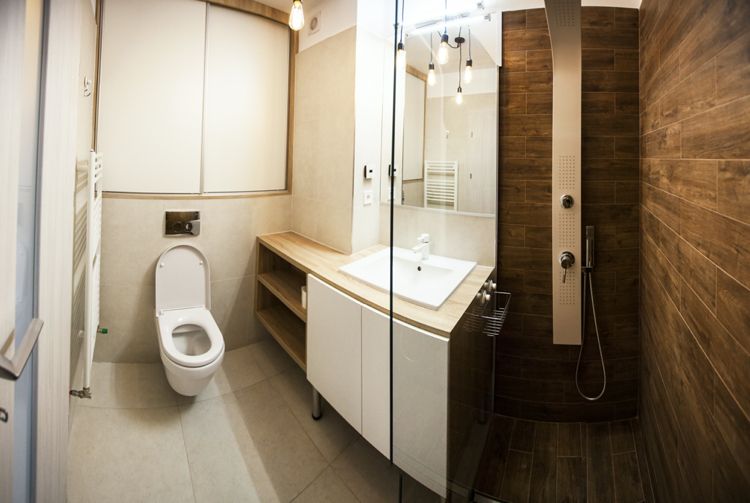 litet badrum med duschkabin, inbyggt skåp över inbyggd toalett ger förvaringsutrymme