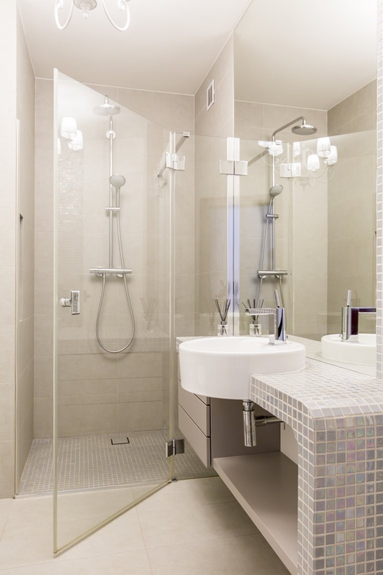 Litet badrum med duschkabin med krämfärgat mosaikgolv