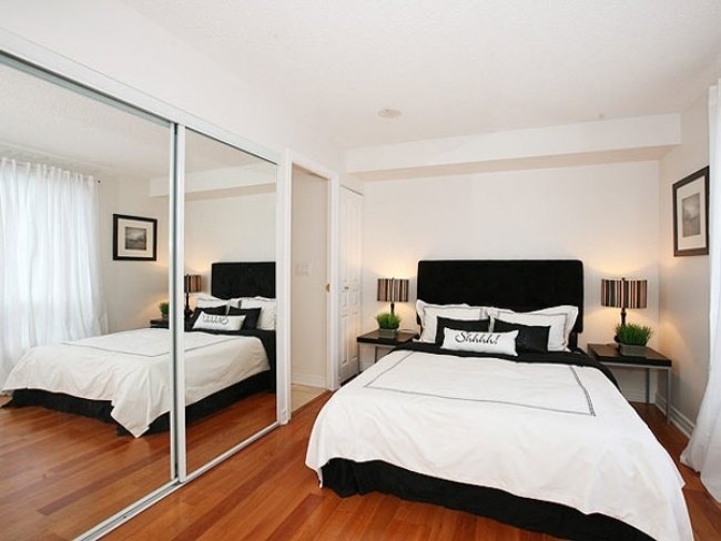 Litet sovrum med svartvita spegeldörrar