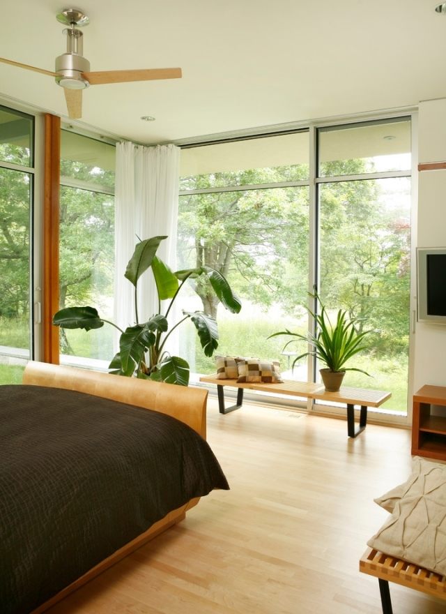 sovrum med stora fönster fram laminat-trä säng-krukväxter