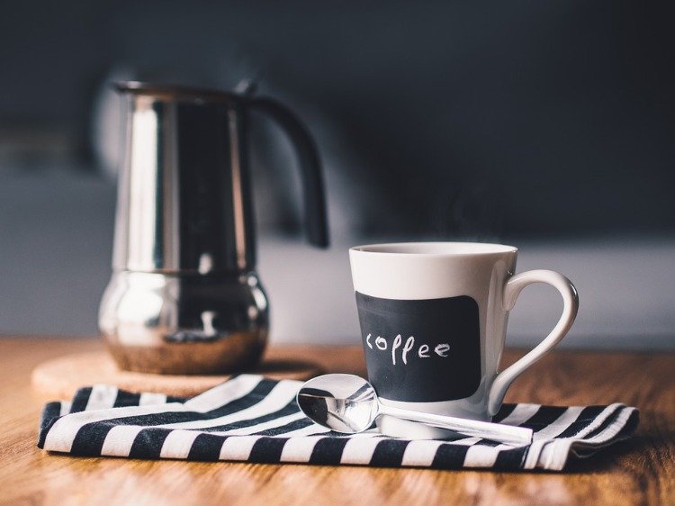 Morgonkaffe med gryta och sked på den vikta duken och träbordet