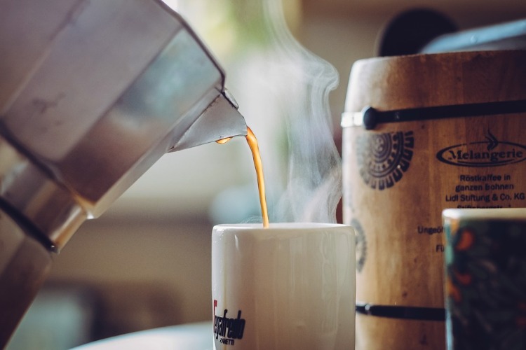 Häll varmt ångande kaffe från grytan i koppen