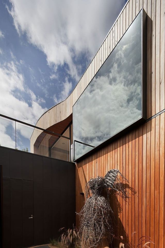 Övre golv-glas-vägg-reflekterar-sky-igen-trä fasad