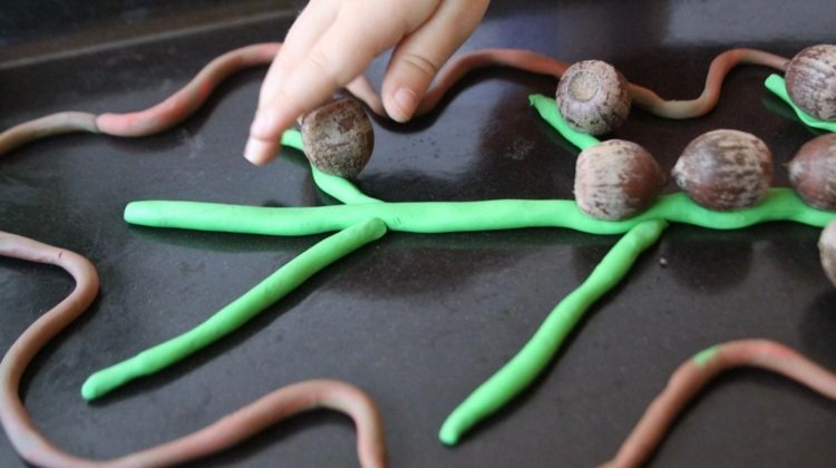 Knådar med barn på hösten och främjar finmotorik med blad av plasticine och ekollon