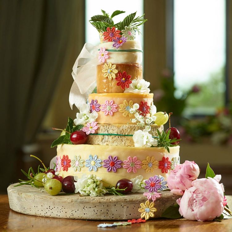 Färgglad bröllopskaka med spetsblommor och frukter