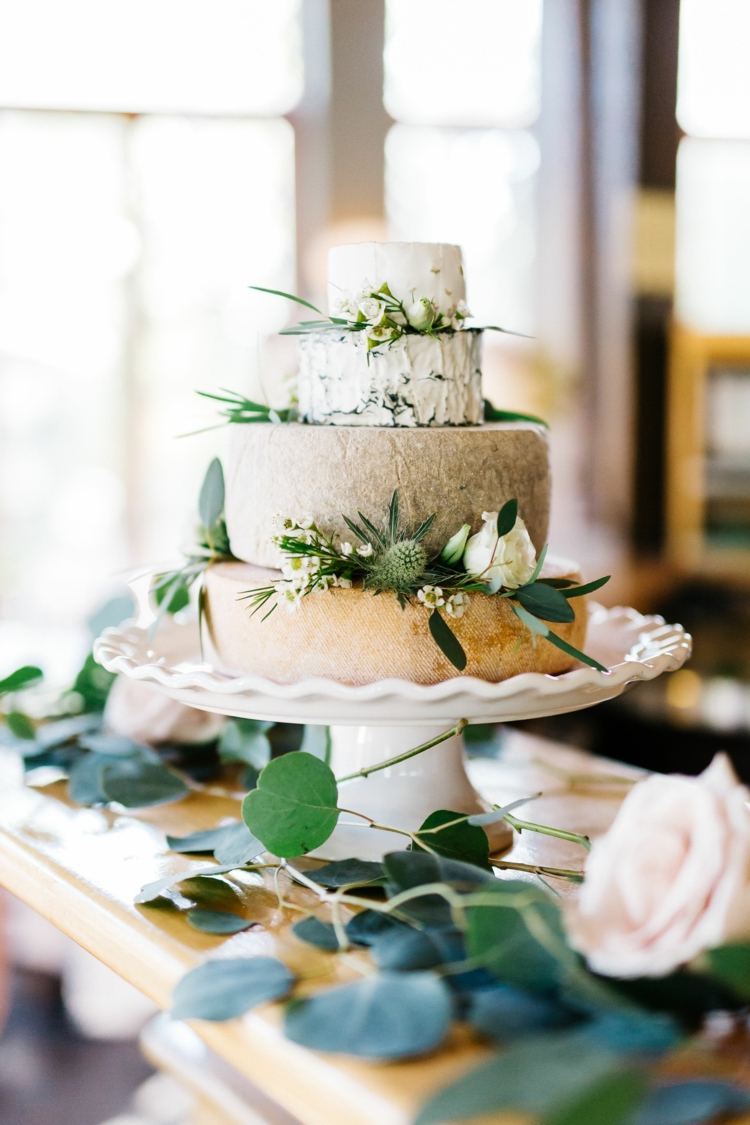 Vintage ostbröllopstårta med grön och vit dekoration gjord av blommor och blad