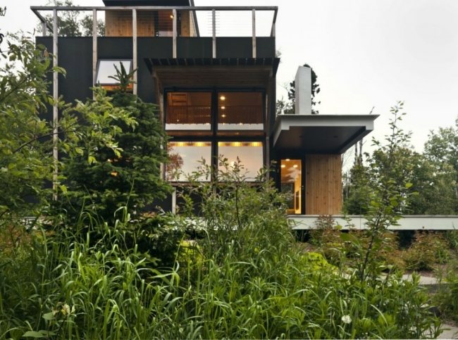 Modern huskoja på en panoramafönster-svart fasad i en sluttning