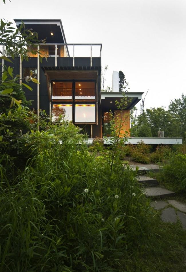 Hus på en sluttning glasväggar öppningsbara fönster-vägg trädäck terrass-tak stenlagda