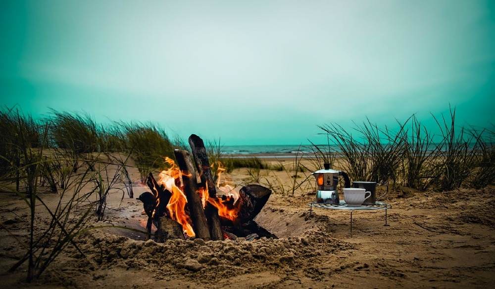 brinnande lägereldrecept på stranden med kaffe och matlagningsgrillcamping