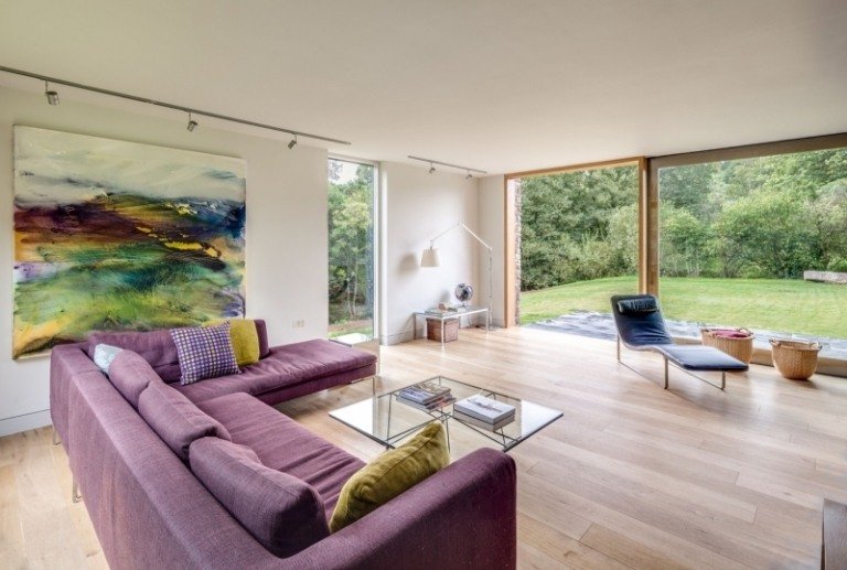 lantlig-modern-arkitektur-inredning-vardagsrum-trä-golv-hörn-soffa-violett-klädsel-bild-suddiga-färger