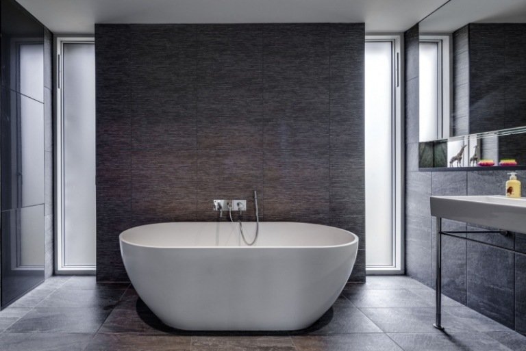 lantlig-modern-arkitektur-inredning-badrum-grå-natursten-kakel-fristående-badkar-enkel