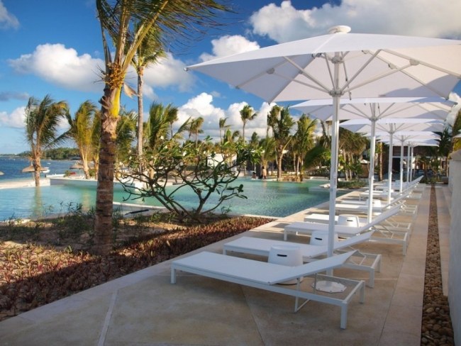 Hotellpool modern anläggning, vita solstolar, parasoller, solstolar