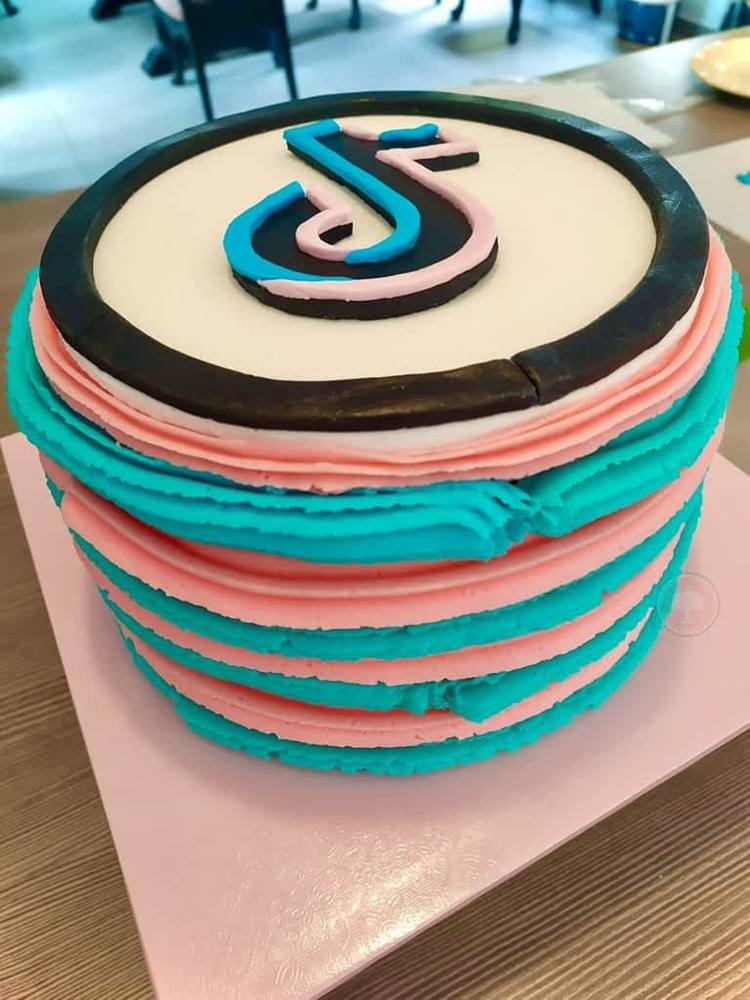 Gör en enkel TikTok -tårta själv med grädde i blått och rosa och TikTok -logotypen