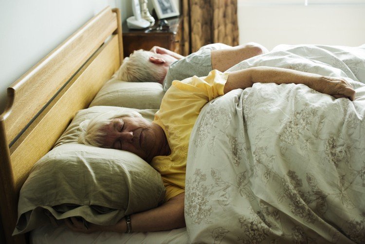 Hård eller mjuk madrass för ryggsmärta Äldre par som ligger i sängen