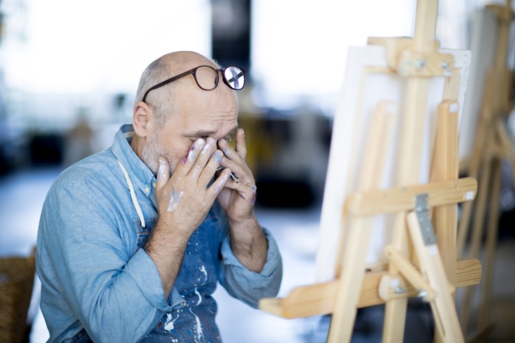 målaren håller ögonen med händerna på grund av trötthet