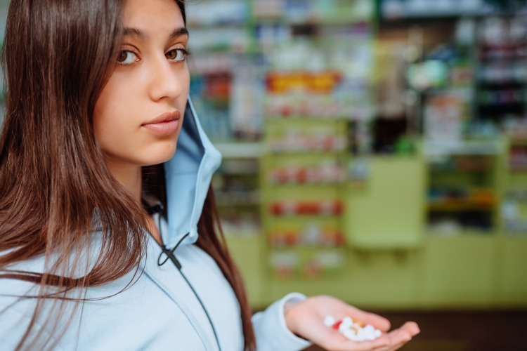 ung kvinna med skyddsmask i apoteket håller medicin mot depression i handen