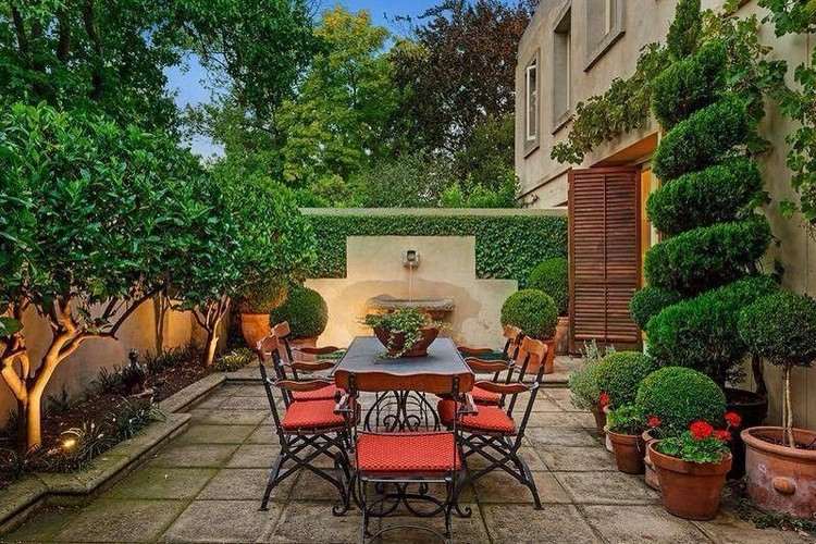 Medelhavet trädgårdsterrass-smidesjärn-möbler-orange-sittdynor-buxbom-sockerbrödgran topiary