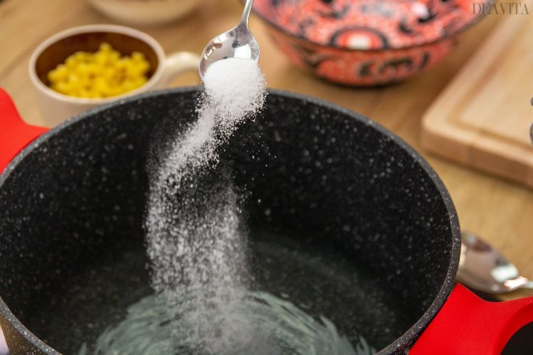 gryta med kokande vatten salt strö nudlar