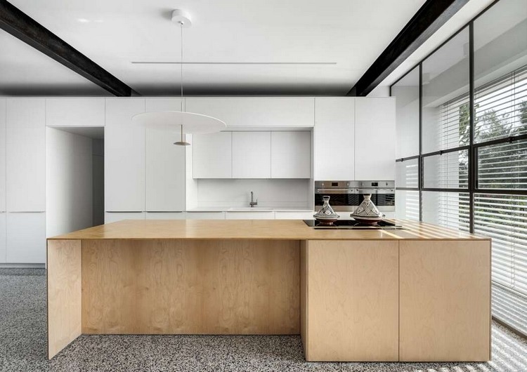 träfärgad köksö med matplats i ett rymligt kök med vita skåp från golv till tak och en fönsterfront