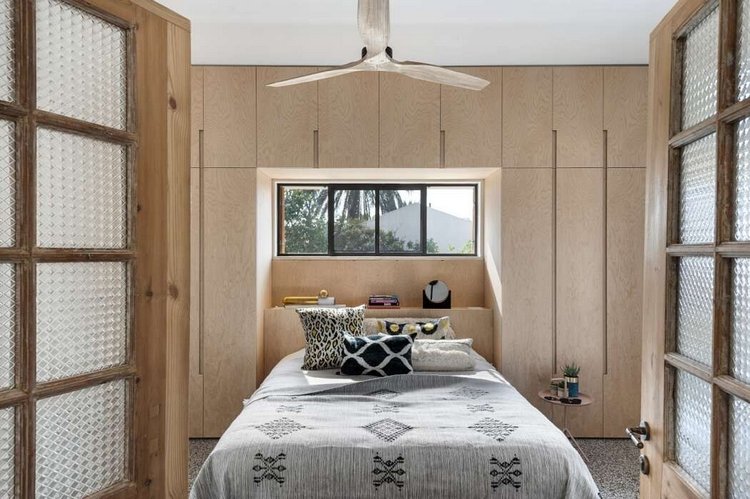 smalt sovrum med golv-till-tak-skåp och en dubbelsäng i retrostil