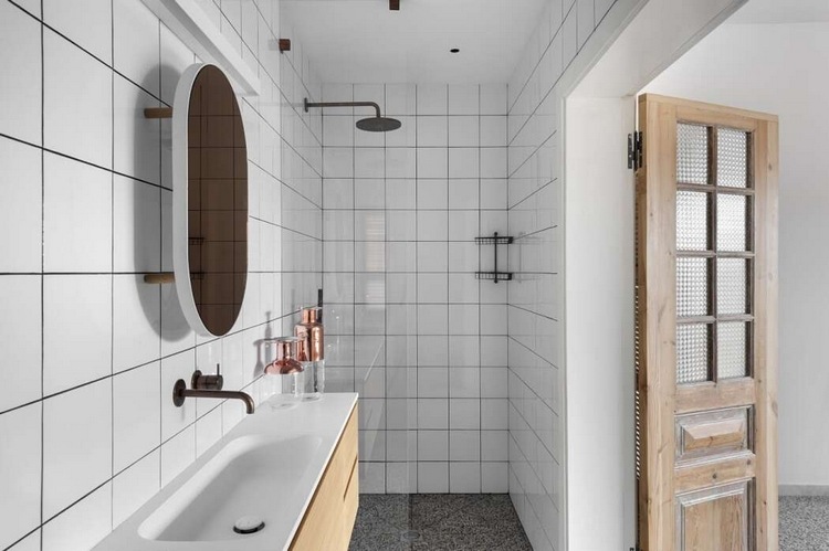minimalistiskt badrum med duschkabin i vit kakel och vikdörrar i trä