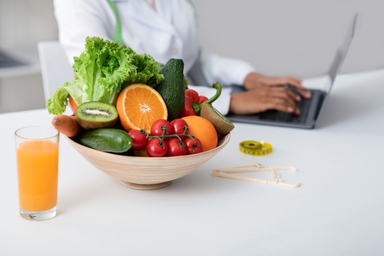 Nutritionist skriver matbord som en kost av frukt och grönsaker för att gå ner i vikt på en bärbar dator