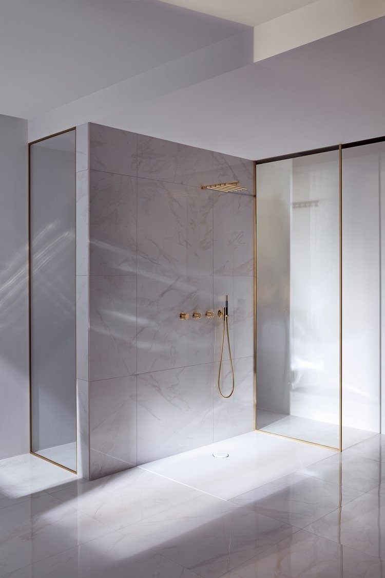Minimalism i badrummet, duschkabin på golvnivå och duschsystem för väggmontering i mässingslook