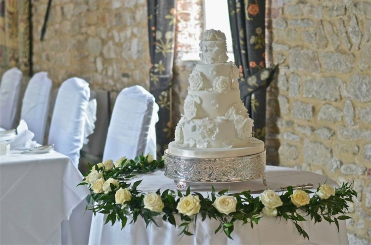 bröllopstårtan med markerad av en ädel blommig krans med vita rosor